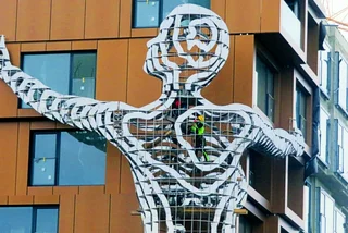Massive new David Černý sculpture holds up a Prague apartment building
