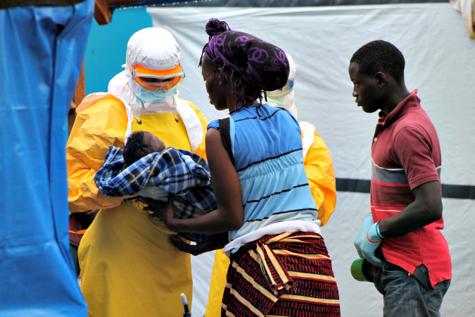 © Martin Zinggl/MSF: An MSF doctor takes a child whose mother died from Ebola in the CMC, 2014.