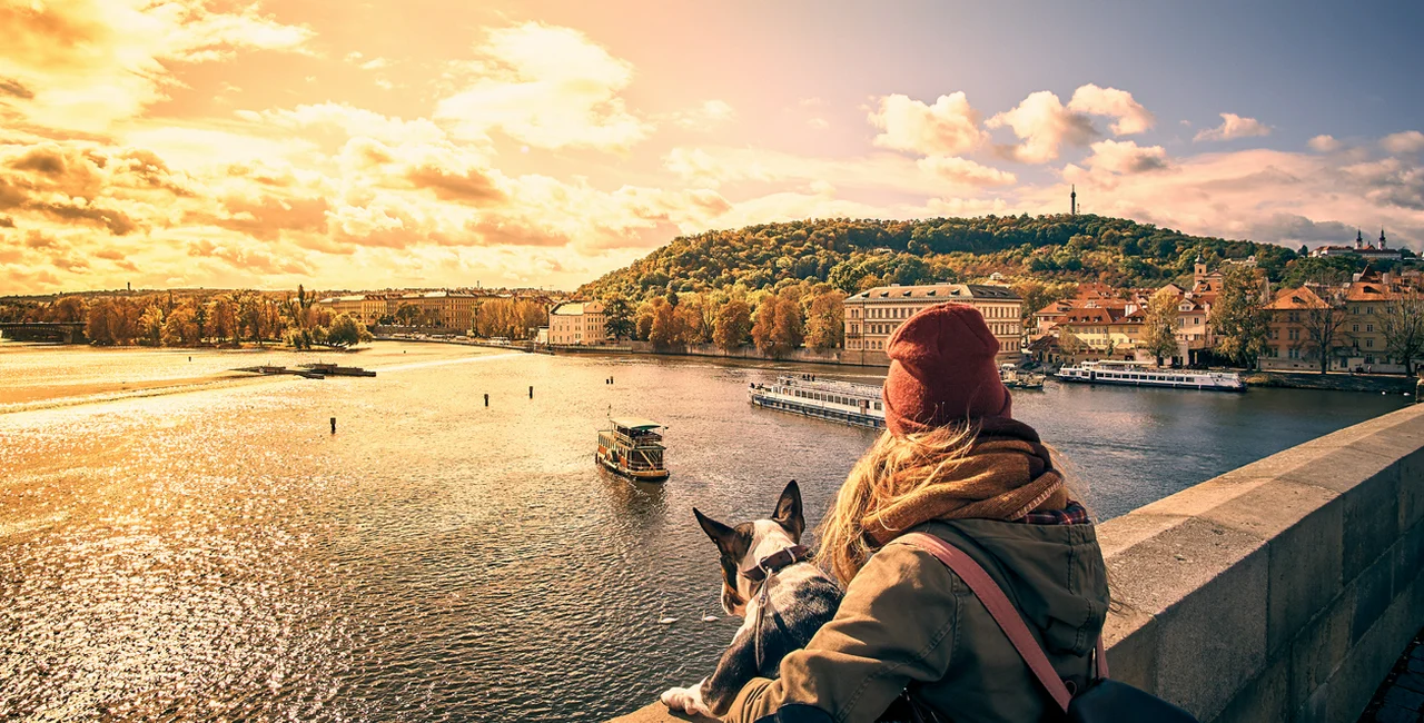 A young woman and her dog take in a view overlooking the Vltava River from Prague's Charles Bridge