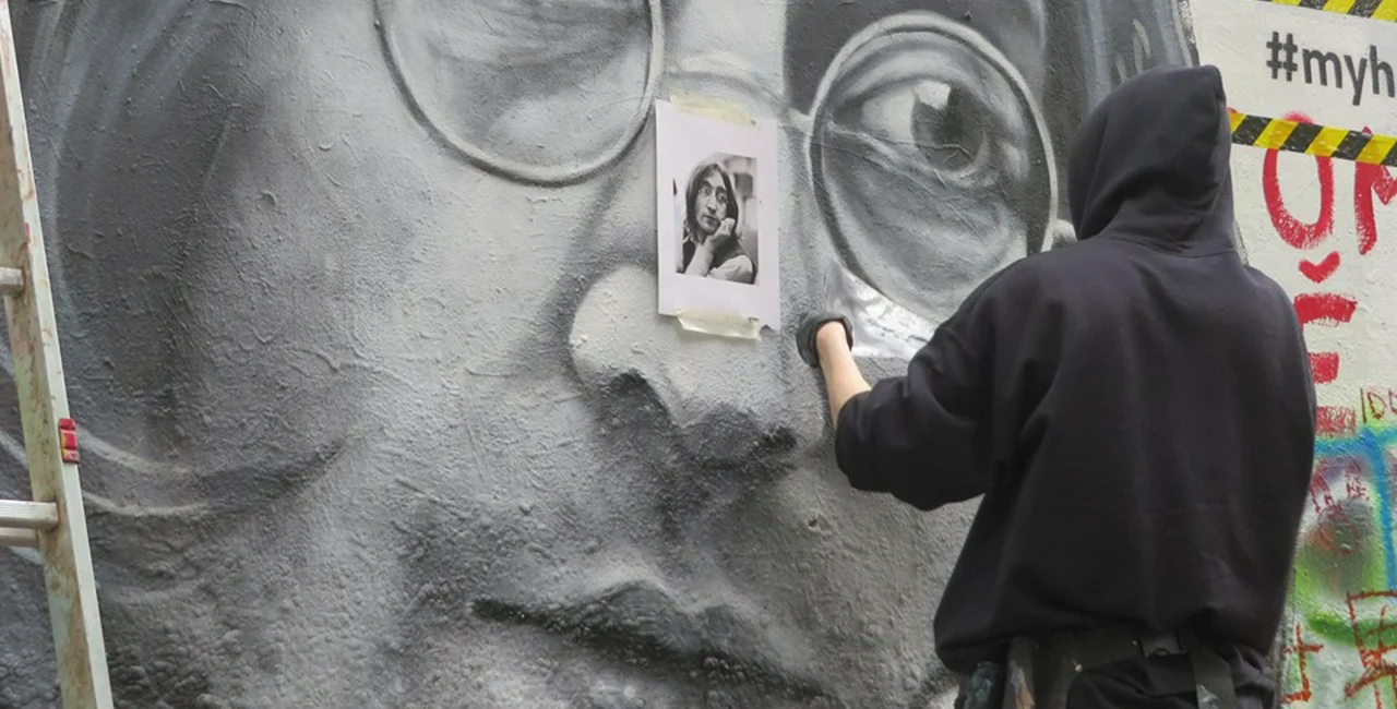 An artist makes a new portrait of John Lennon on Prague's Lennon Wall. via Raymond Johnston