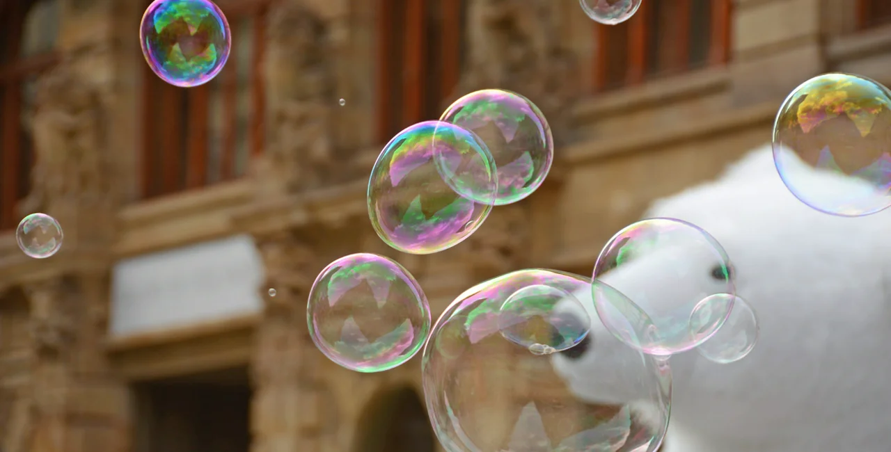Prague: Soap bubbles in the city centre of Prague. in the background a defoced street bear, and building facade.