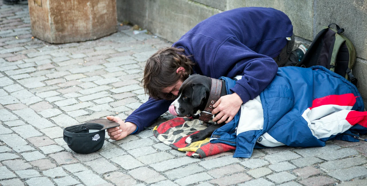 November 30, 2018: A homeless man with a dog pictured begging on Prague's Charles Bridge