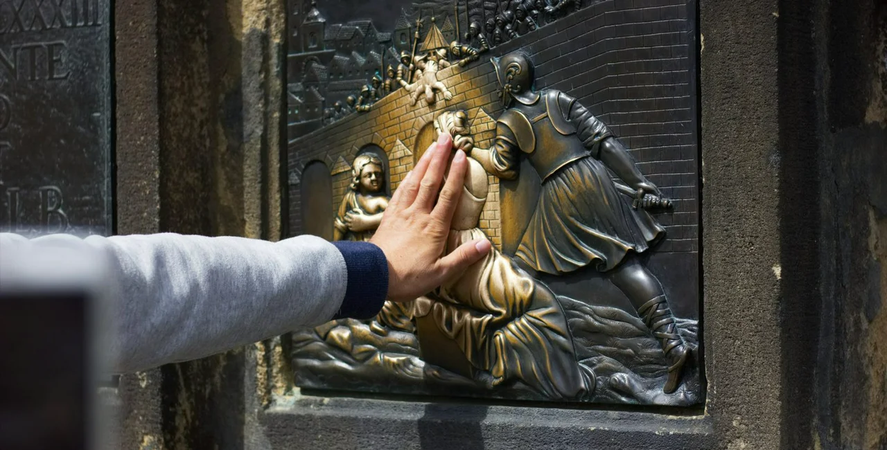 Making a wish on the St. John of Nepomuk Statue, Charles Bridge, Prague, Czech Republic