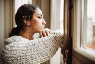 Pensive young woman in front of a window (illustrative photo)
