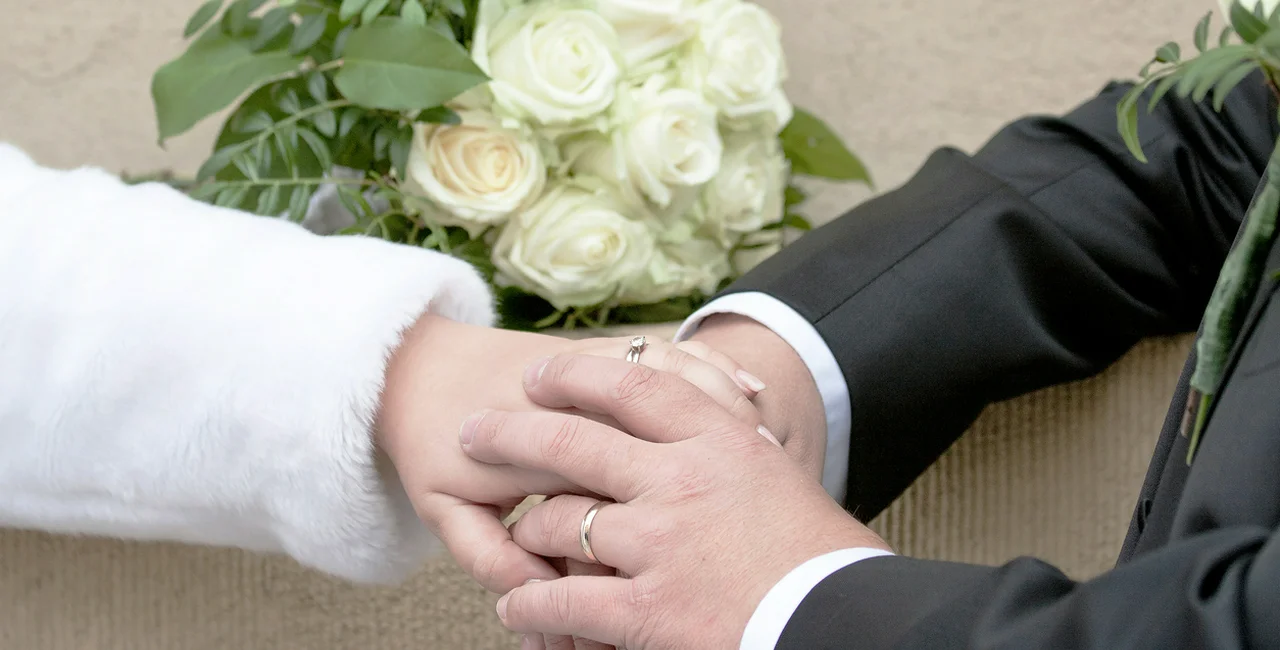 Hands of a bride and groom with a wedding ring in Prague