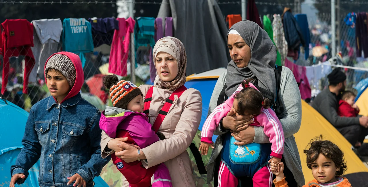 Eidomeni, Greece - March 17, 2016: Two women walk with their children in a refugee camp