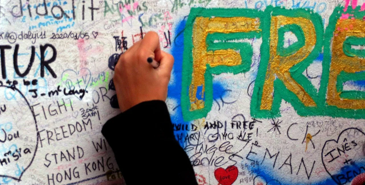 A tourist writes on the Lennon Wall. via Raymond Johnston