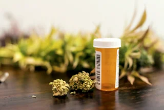 Marijuana buds sitting next to prescription medicine bottle (via iStock / FatCamera)
