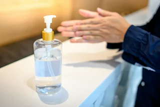 Using an alochol-based sanitizer to clean hands via iStock / Zephyr18