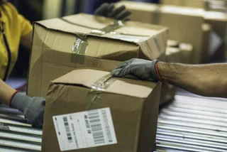 Postal workers handling boxes. Illustrative image via iStock.com / vm