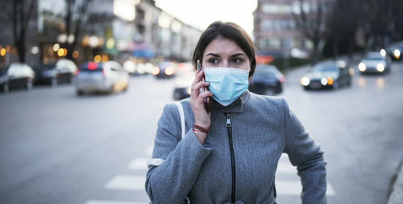 Woman with mask talking on the phone. Illustrative photo via iStock.com / ArtistGNDphotography