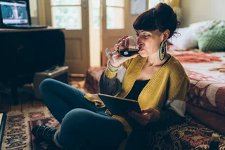 Young woman at home drinking red wine via iStock / martin-dm