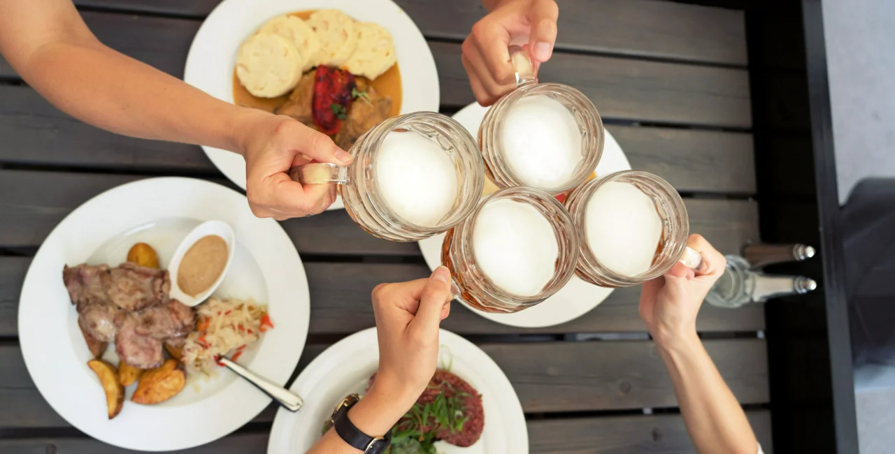 Friends raising their beer glasses and making a toast / photo iStock @kamisoka