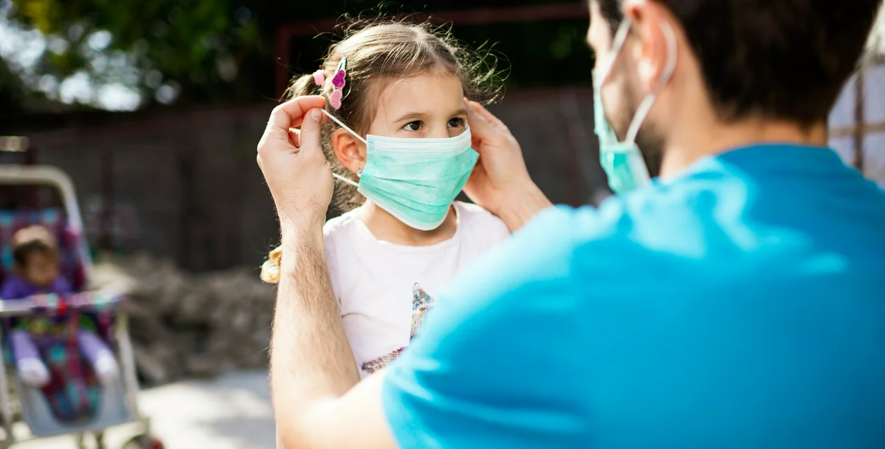 Father applying face mask to his daughter via iStock / SanyaSM