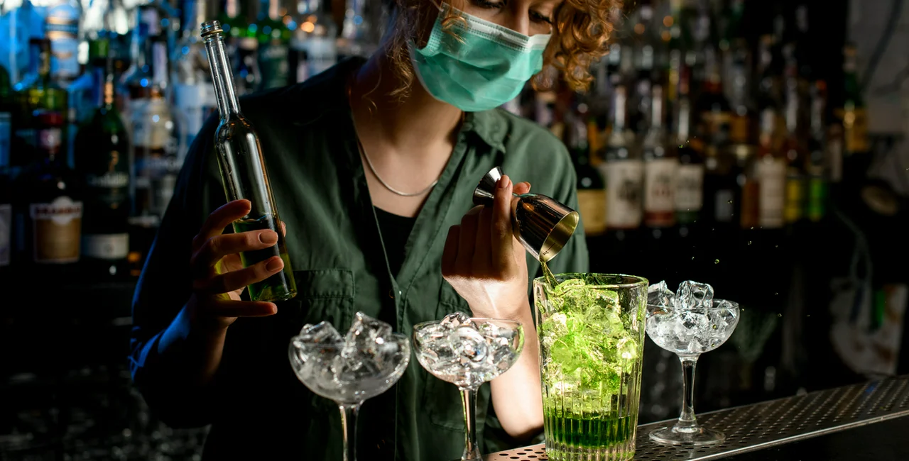 A bartender wearing a face mask pours a mixed drink. Illustrative photo via iStock / MaximFesenko
