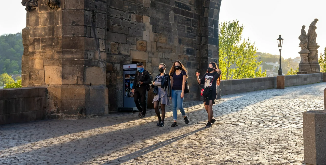 People wearing face masks on a mostly-empty Charles Bridge in Prague in April via iStock / Madeleine_Steinbach