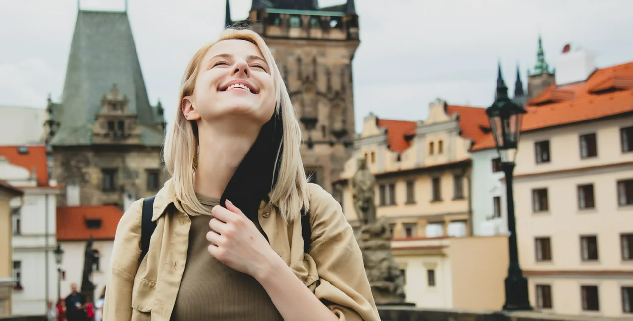 A woman removes her face mask on Prague's Charles Bridge. With the exception of the metro, masks are no longer required in the Czech capital. Photo via iStock / Massonstock