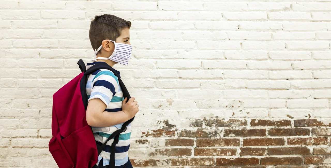 Young boy going to school with protective mask via iStock / coscaron