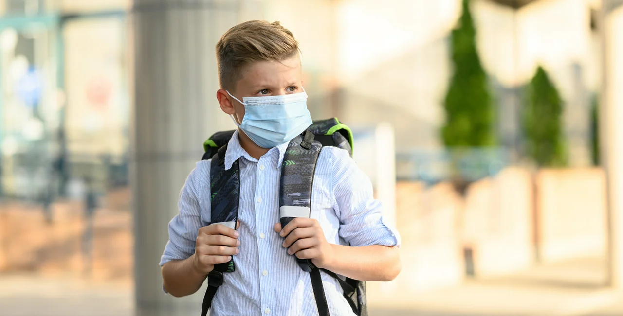 Young boy going to school with protective face mask on via iStock / DjelicS