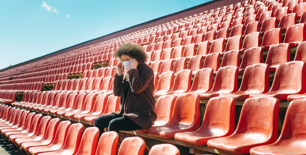 Woman wearing a face mask at an empty stadium via iStock / IRYNA KAZLOVA