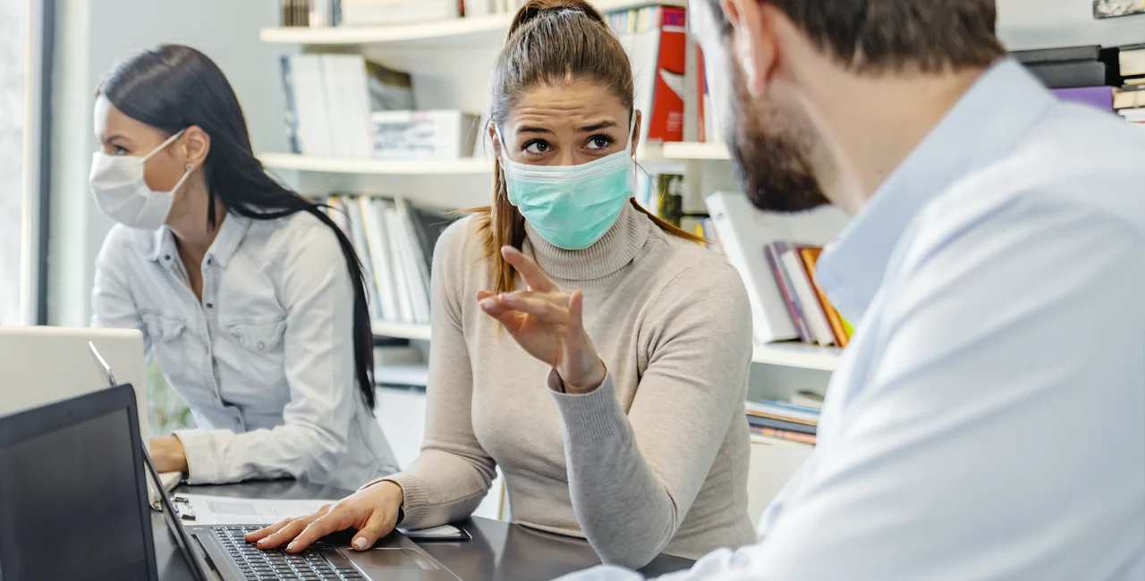 Co-workers wearing face masks via iStock / ljubaphoto