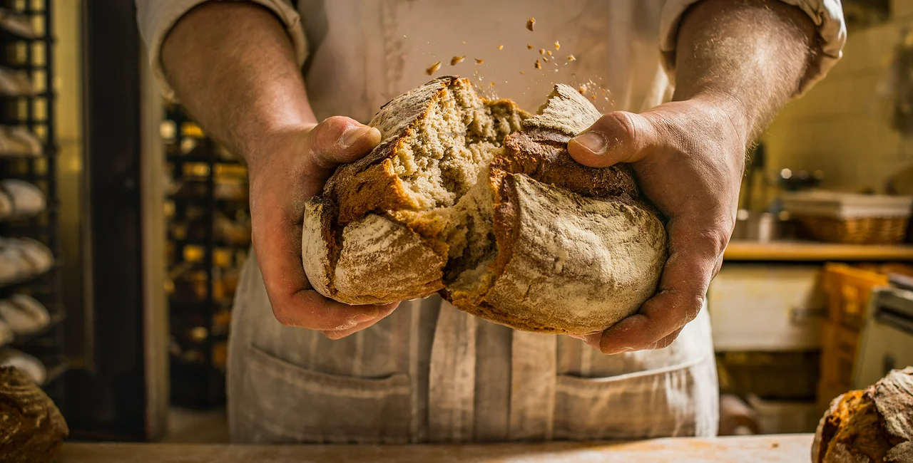 baker breaking a loaf of bread