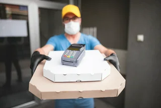 A man wearing a mask delivers take out food. Photo: iStock/m-gucci