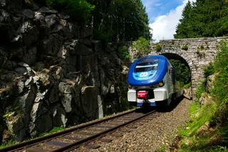 Ceske drahy CD railway train passes under a stone bridge in the Ore Mountains in Nejdek, Czech Republic. (photo: iStock / josefkubes)
