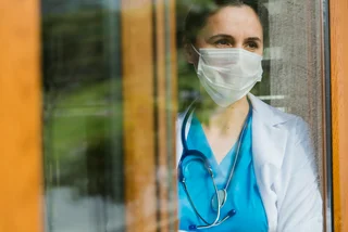 Doctor looking through a hospital window via iStock / aydinmutlu