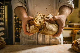 baker breaking a loaf of bread