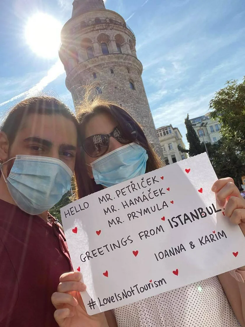 Ioanna and Karim in Turkey together after months of separation, holding up a sign with the hashtag #LoveIsNotTourism. Photo courtesy of the couple.