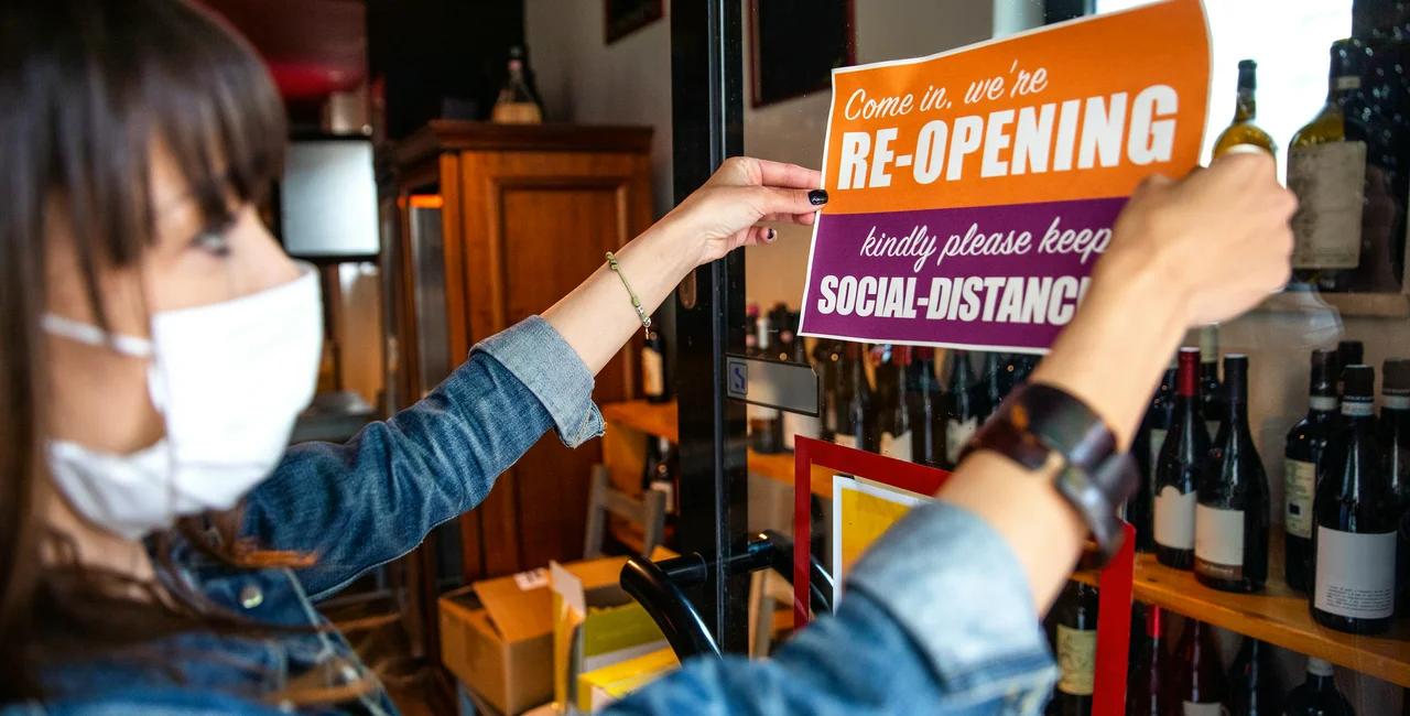 A woman places a sign in a shop window, via iStock / LeoPatrizi