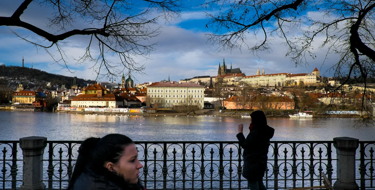 Pedestrians pass by a view of the Prague Castle looking across the Vltava River, along Alšovo nábřeží. (photo: James Fassinger - Expats.cz)