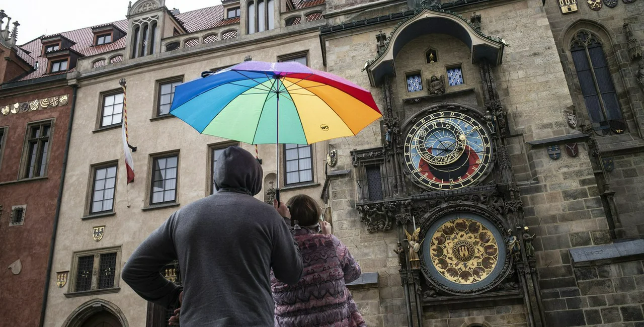 People watch the Astronomical Clock in the rain / via iStock