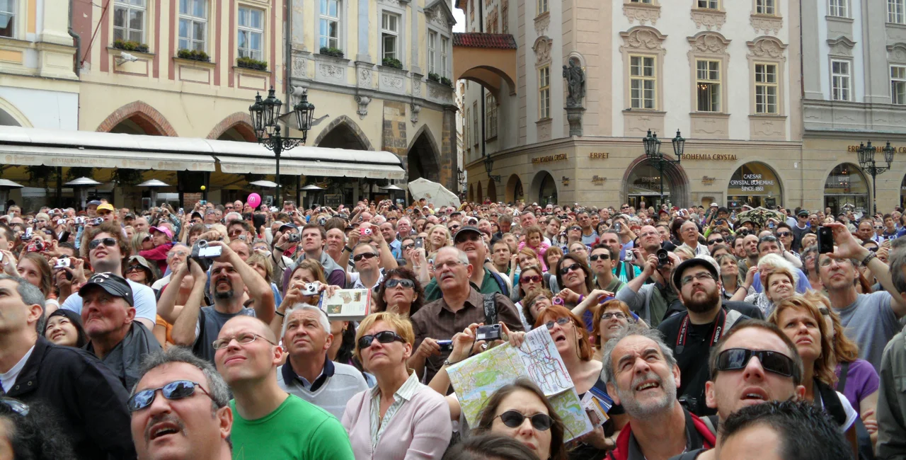 People looking up at Old Town Square clock, Prague. (photo: iStock / TiagoArq)