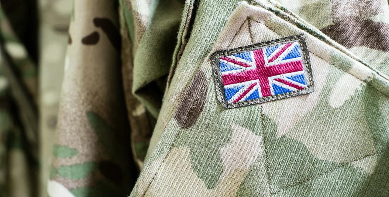 Union Jack flag on the sleeve of British military camouflage uniform shirt sleeve, via iStock / ikholwadia