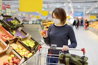 Young woman wearing a face mask in a supermarket via iStock / SbytovaMN