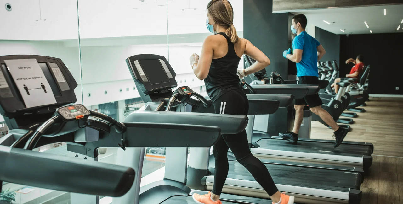 Runners on treadmills at the gym wearing face masks via iStock / svetikd