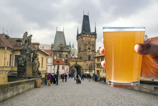 Man holding glass of light beer with view of Charles Bridge in Prague, Czech Republic (iStock photo / Maria Vonotna)