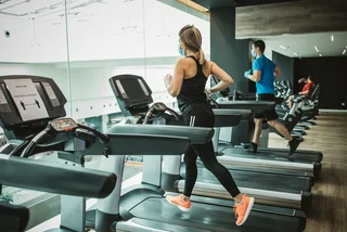 Runners on treadmills at the gym wearing face masks via iStock / svetikd