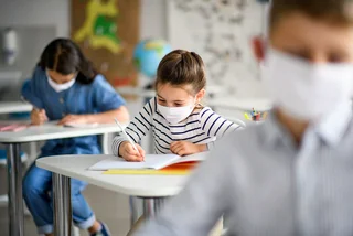 Children wearing face masks at school via iStock / Halfpoint