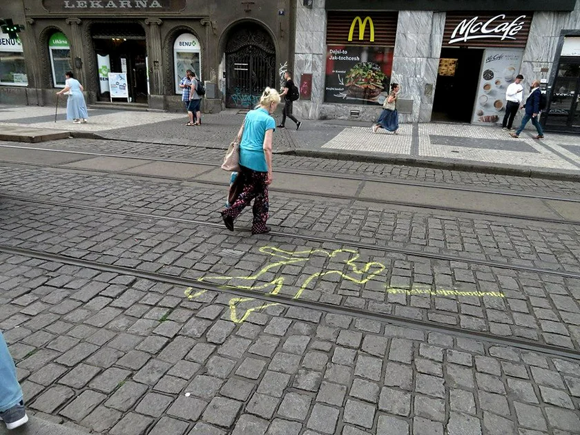 A woman crosses the tram tracks next to a safety warning sign. (photo: Raymond Johnston)