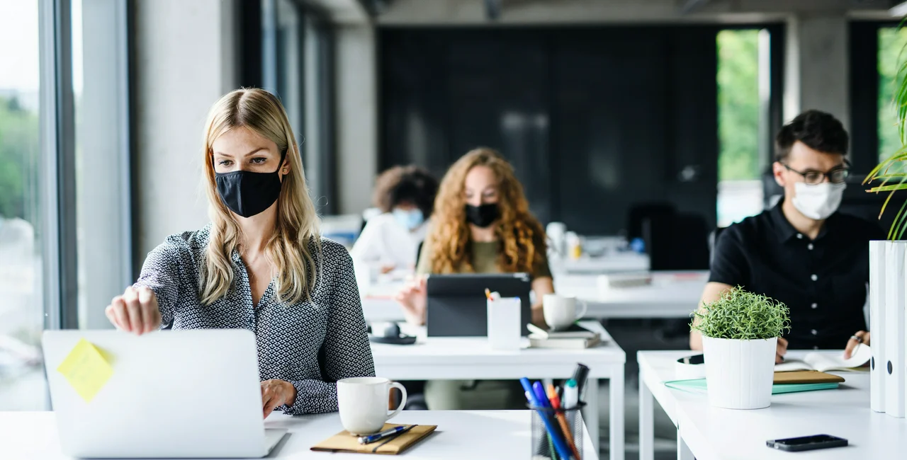 Young people in office wearing face masks via iStock / Halfpoint