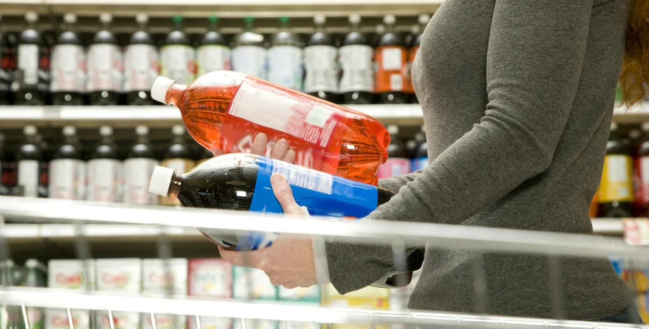 A shopper compares the labels of two beverages. (Photo: iStock, FangXiaNuo)