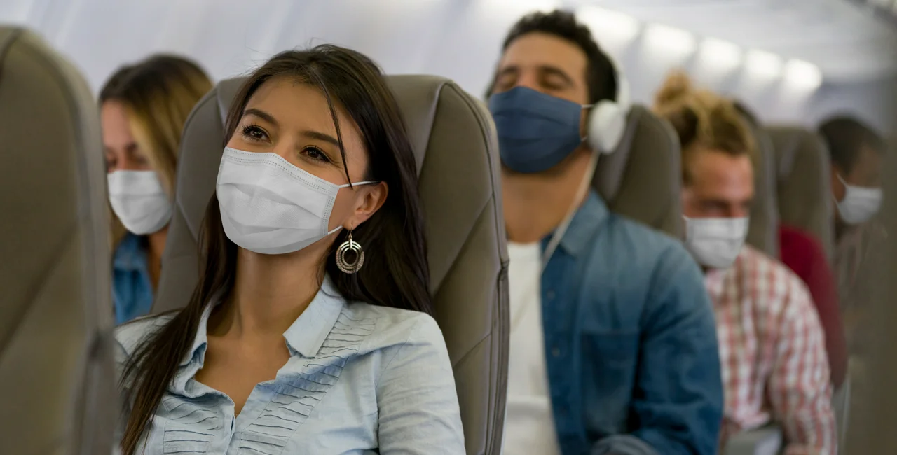 People traveling by place in face masks. (Moderna: iStock, Hispanolistic)
