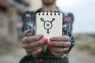 Person holding a trans symbol on a notebook. (Photo: iStock, nito100)