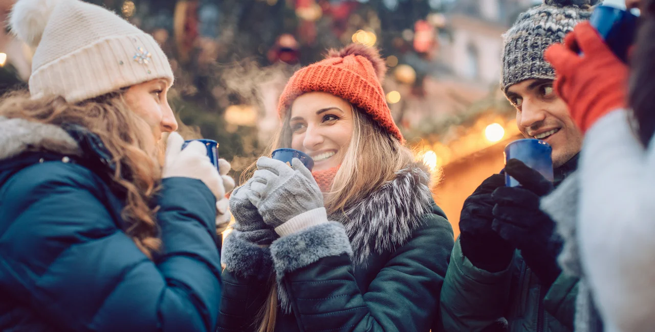 Group of friends drinking mulled wine at a Christmas market. Photo: iStock /