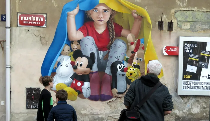 People look at a mural depicting a Ukrainina child sheltering under a flag. Photo: Raymond Johnston.