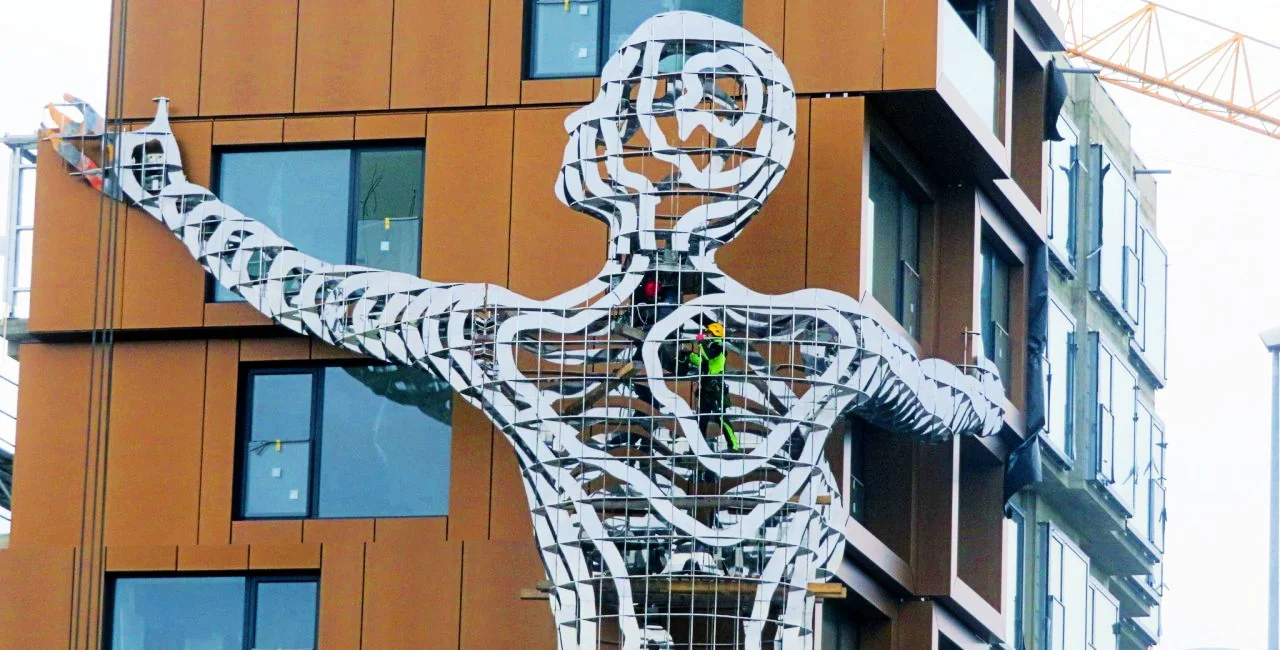 Massive new David Černý sculpture holds up a Prague apartment building