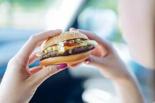 Woman eating a fast food hamburger. Photo: iStock / Wojciech Kozielczyk